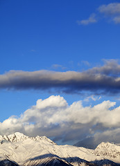 Image showing Snow winter mountains in clouds at sun evening