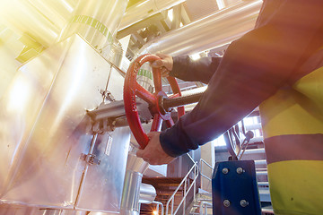 Image showing factory worker turning valve