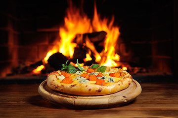 Image showing pizza with a pumpkin on  background of fire. Dish  Halloween