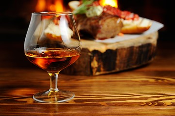 Image showing glass of cognac on the background  a meat dish