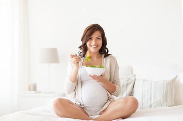 Image showing happy pregnant woman eating salad at home