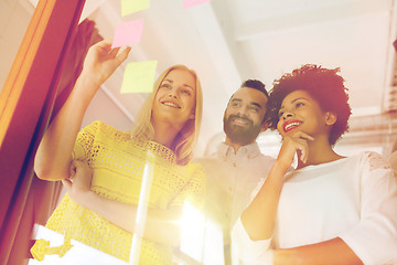 Image showing happy creative team writing on stickers at office