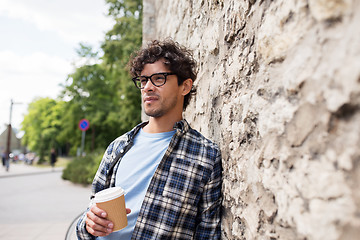 Image showing man in eyeglasses drinking coffee over street wall