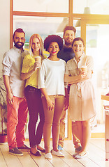 Image showing happy smiling creative team with coffee in office