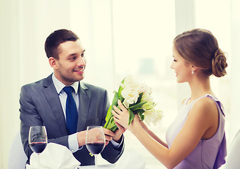 Image showing smiling man giving flower bouquet at restaurant