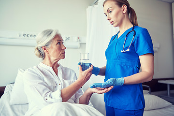 Image showing nurse giving medicine to senior woman at hospital