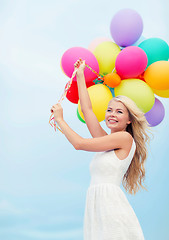 Image showing smiling woman with colorful balloons outside