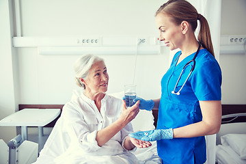 Image showing nurse giving medicine to senior woman at hospital