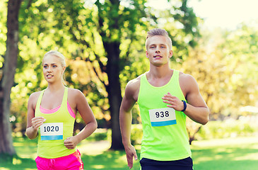 Image showing happy sportsmen couple racing wit badge numbers