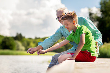 Image showing grandfather and grandson sitting on river berth