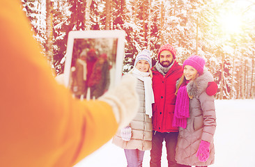 Image showing smiling friends with tablet pc in winter forest