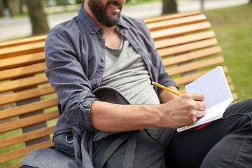 Image showing close up of man writing to notebook on city street