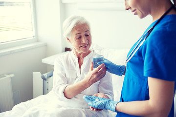 Image showing nurse giving medicine to senior woman at hospital