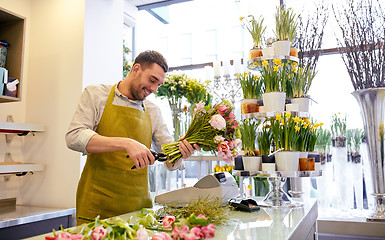 Image showing smiling florist man making bunch at flower shop