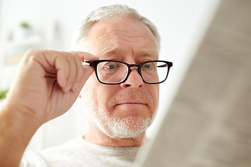 Image showing close up of old man in glasses reading newspaper 