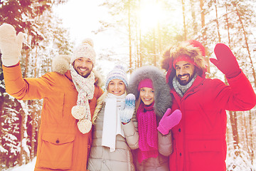 Image showing group of friends waving hands in winter forest