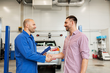 Image showing auto mechanic and man shaking hands at car shop