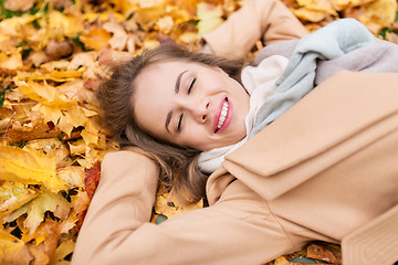 Image showing beautiful happy woman lying on autumn leaves