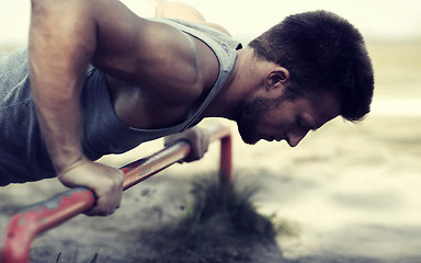 Image showing young man exercising on horizontal bar outdoors