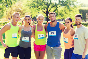 Image showing happy friends or couple with racing badge numbers