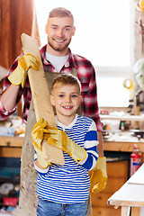 Image showing happy father and son with wood plank at workshop