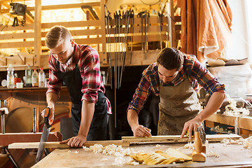 Image showing carpenters working with saw and wood at workshop