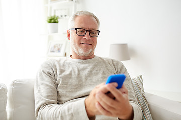 Image showing happy senior man texting on smartphone at home