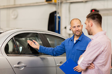 Image showing auto mechanic with clipboard and man at car shop