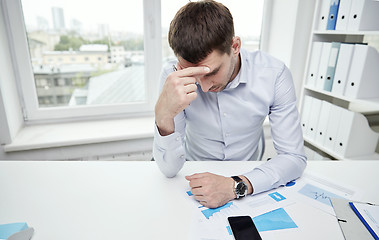 Image showing stressed businessman with papers in office