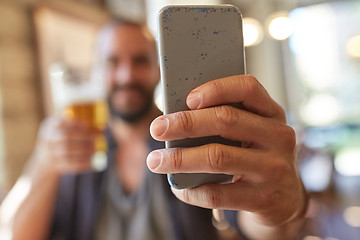 Image showing close up of man with smartphone and beer at pub