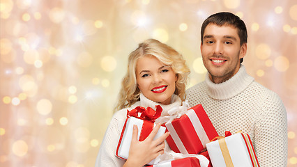 Image showing happy couple in sweaters holding christmas gifts 