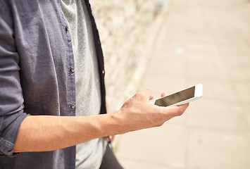 Image showing close up of man with smartphone at stone wall