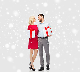 Image showing happy couple with christmas gift boxes over snow