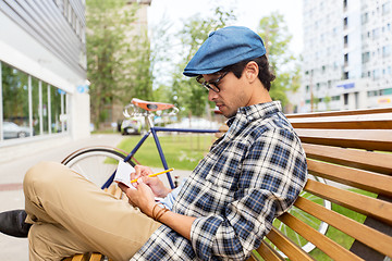 Image showing man with notebook or diary writing on city street