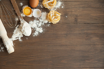 Image showing Cuisine composition with fettuccine cracked eggs,kitchenware, flour.