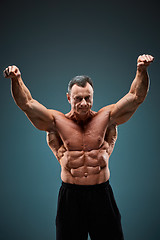Image showing torso of attractive male body builder on gray background.