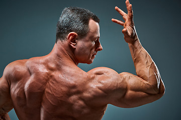 Image showing torso of attractive male body builder on gray background.