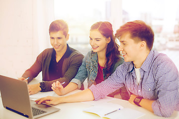 Image showing three smiling students with laptop and notebooks