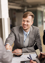 Image showing smiling businessman making handshake at office