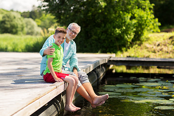 Image showing grandfather and grandson sitting on river berth