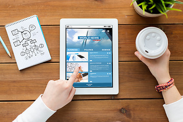 Image showing close up of woman with tablet pc on wooden table