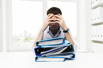 Image showing sad businessman with stack of folders at office