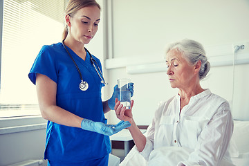 Image showing nurse giving medicine to senior woman at hospital