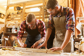 Image showing carpenters with ruler and wood plank at workshop