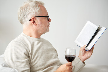 Image showing senior man drinking wine and reading book