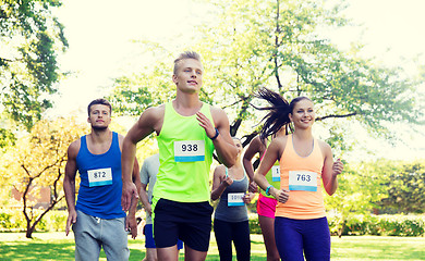 Image showing happy young sportsmen racing wit badge numbers