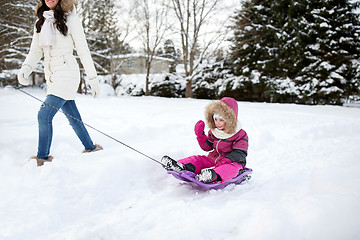 Image showing happy mother pulling sled with child in winter