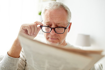 Image showing senior man in glasses reading newspaper at home