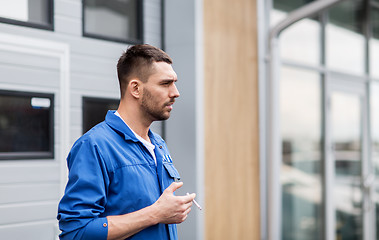 Image showing auto mechanic smoking cigarette at car workshop