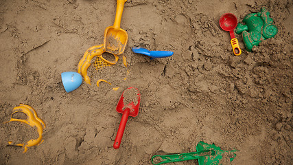 Image showing set of color plastic toys on a sand